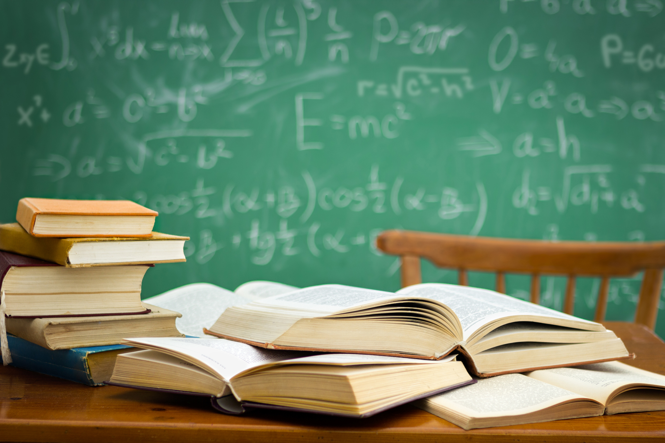 desk in a mess during learning with green blackboard in background